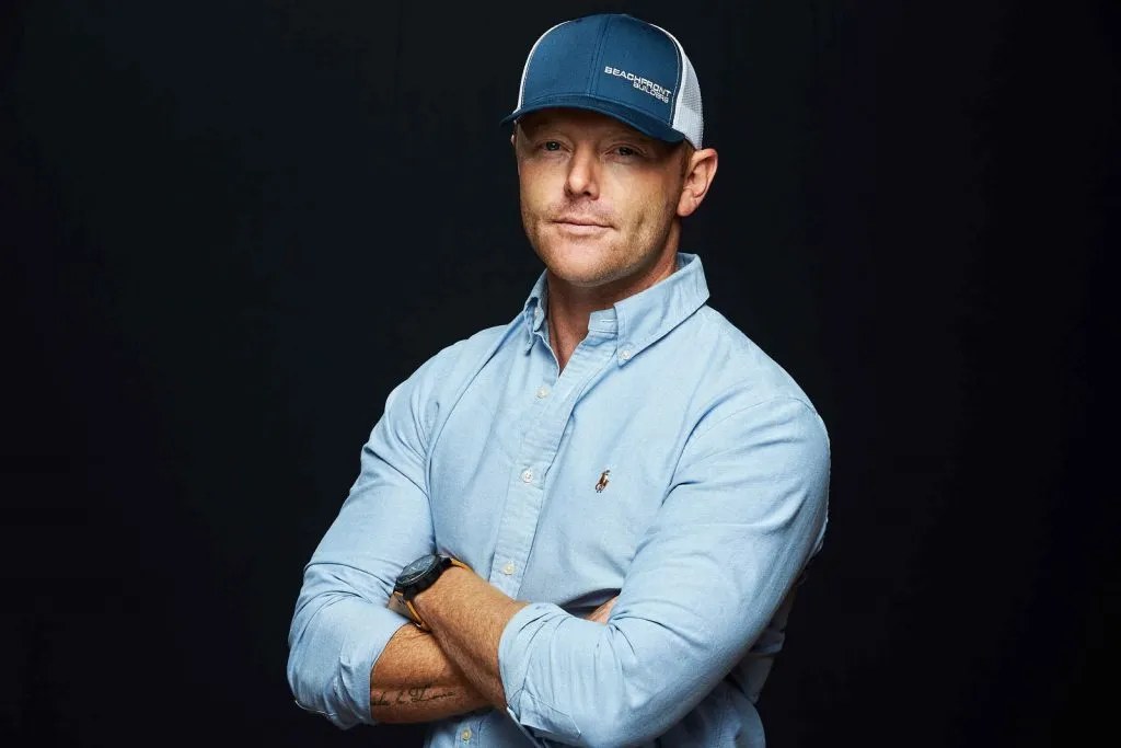 David Shoultz, President of Beachfront Builders, in a Beachfront cap with his arms crossed