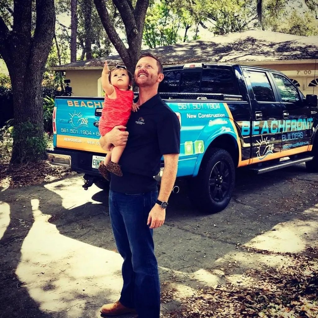 David Shoultz holding his daughter in front of a Beachfront Builders company truck