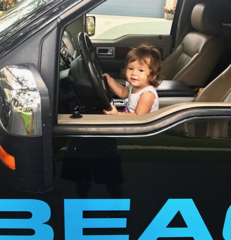 A toddler at the wheel of a Beachfront Builders truck